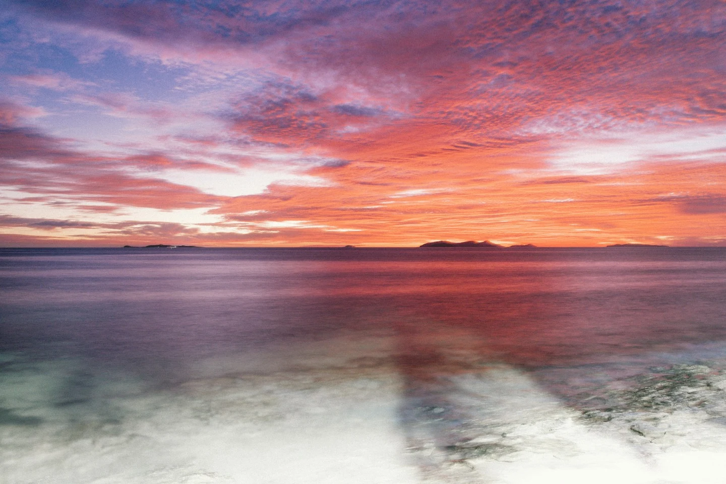 Sonnenuntergang über dem Meer mit Inseln am Horizont