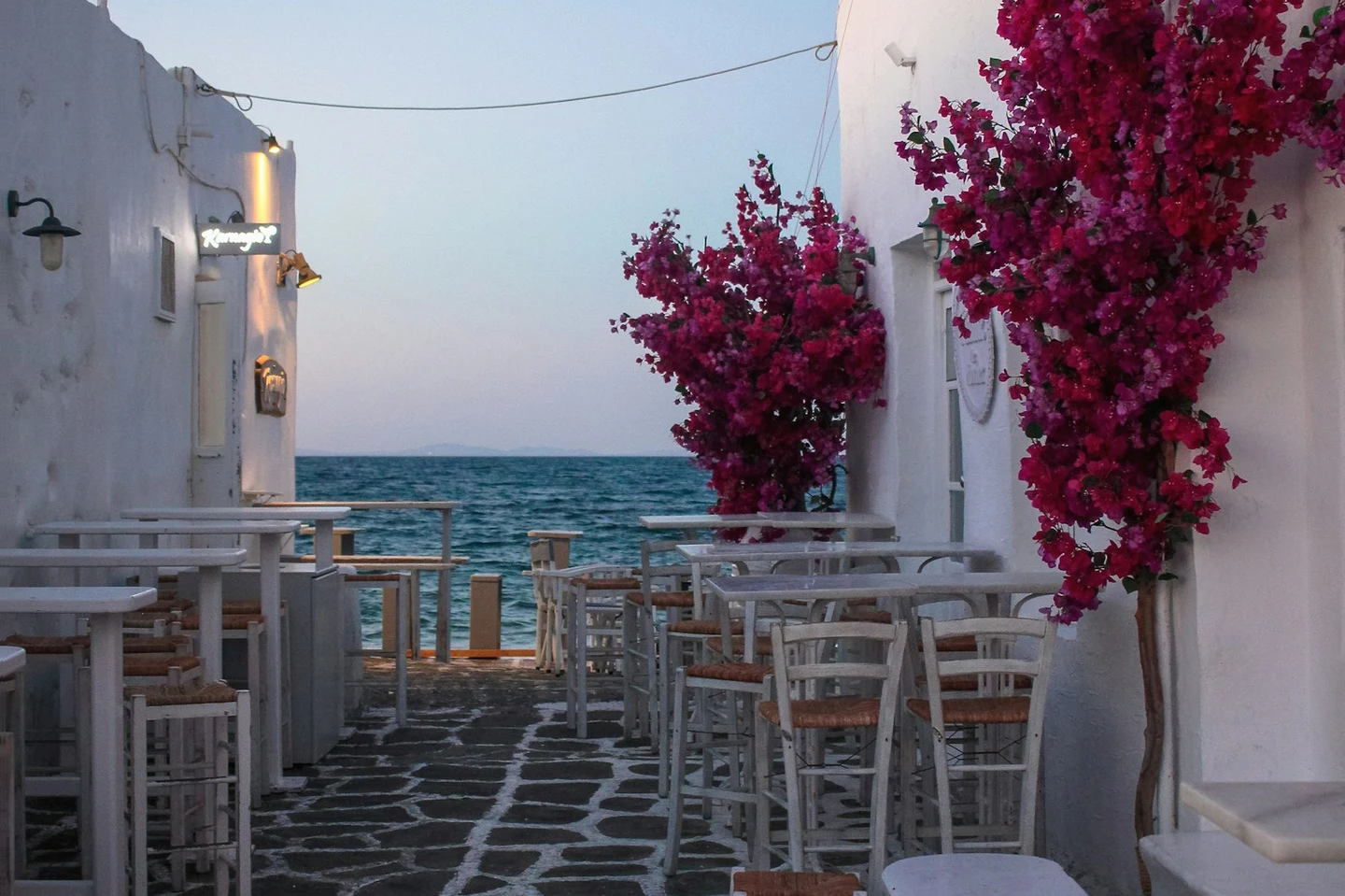 Gasse mit Tavernentischen und Bougainvillea am Meer auf Paros