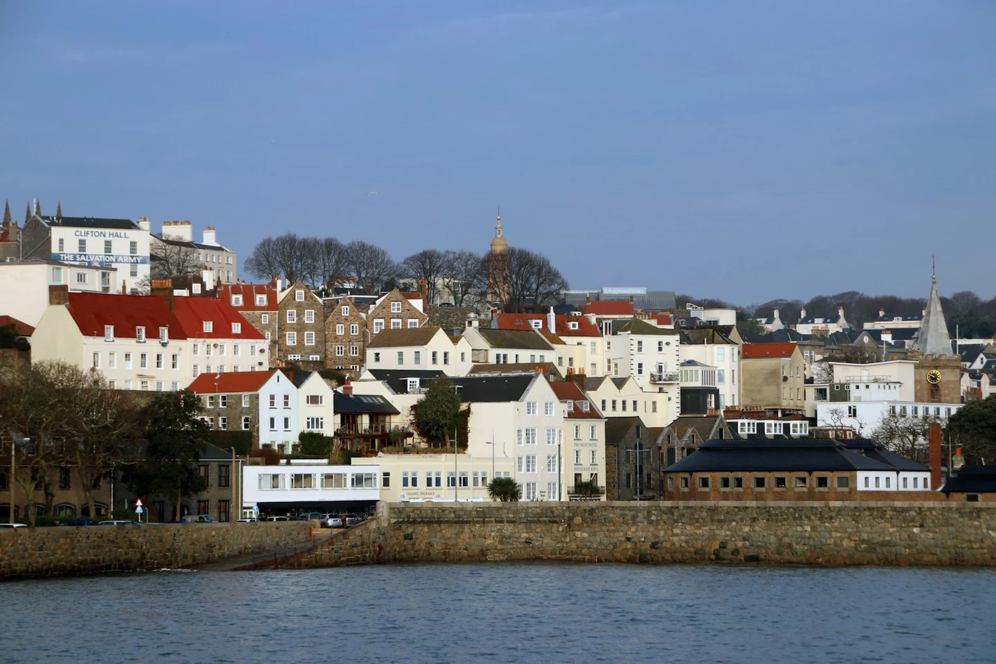 Hafenfront von St. Peter Port mit Stadthäusern und Kirchturm vom Wasser aus