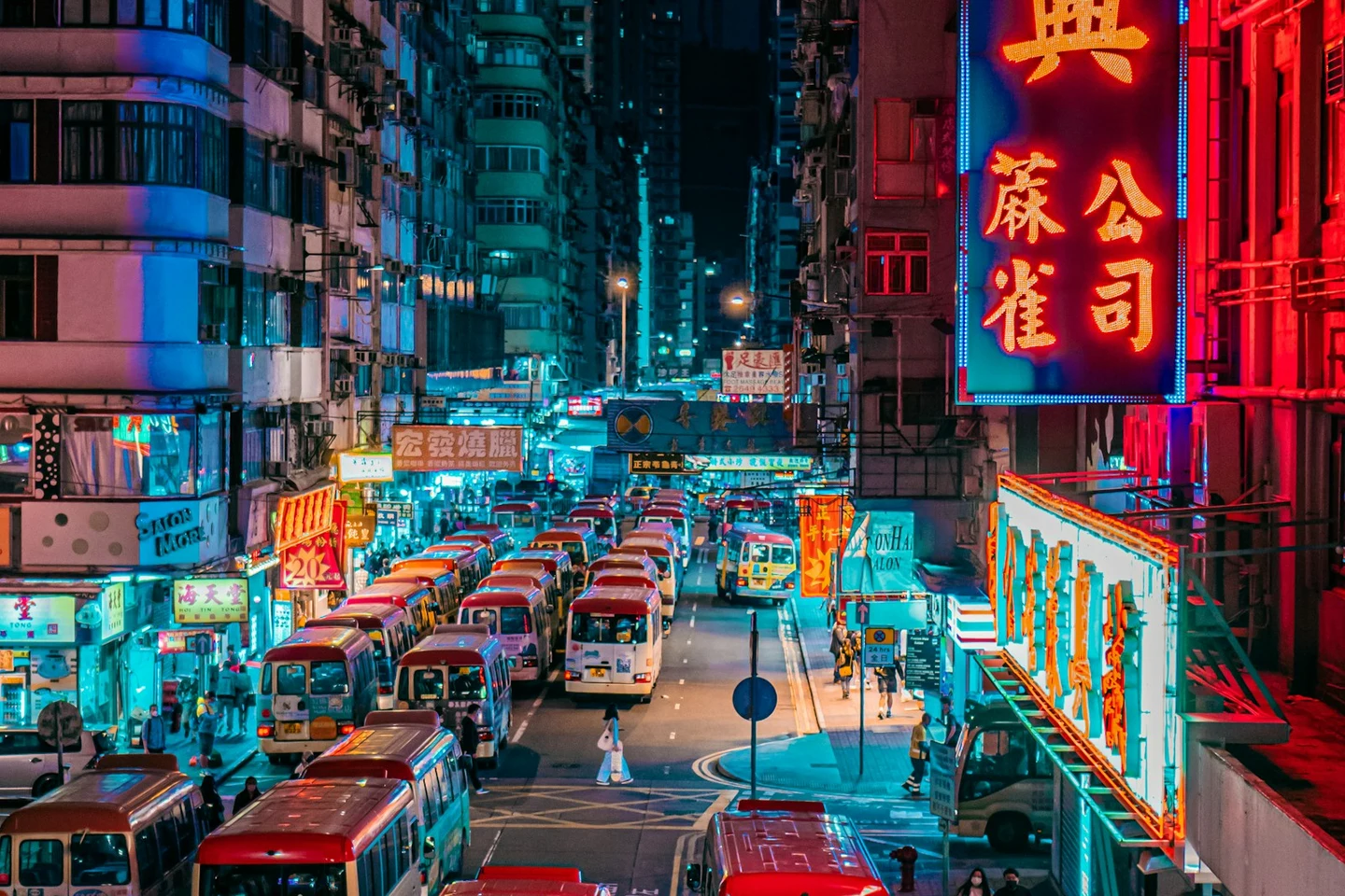 Rot-beige Minibusse in einer neonbeleuchteten Straße in Mong Kok