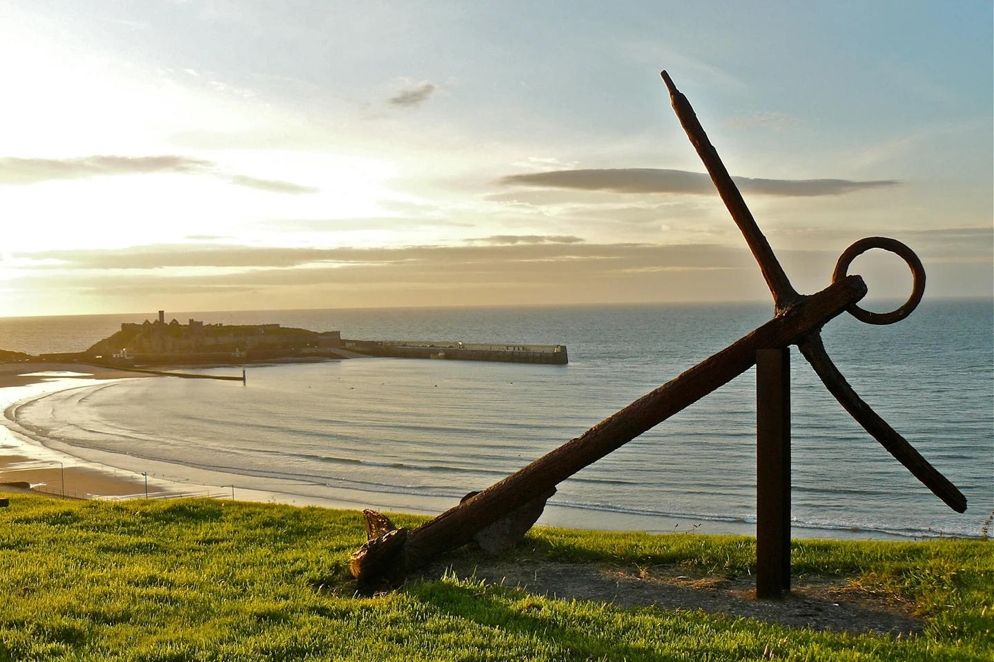 Bucht von Peel mit Strand, Hafenmauer und Peel Castle im Abendlicht