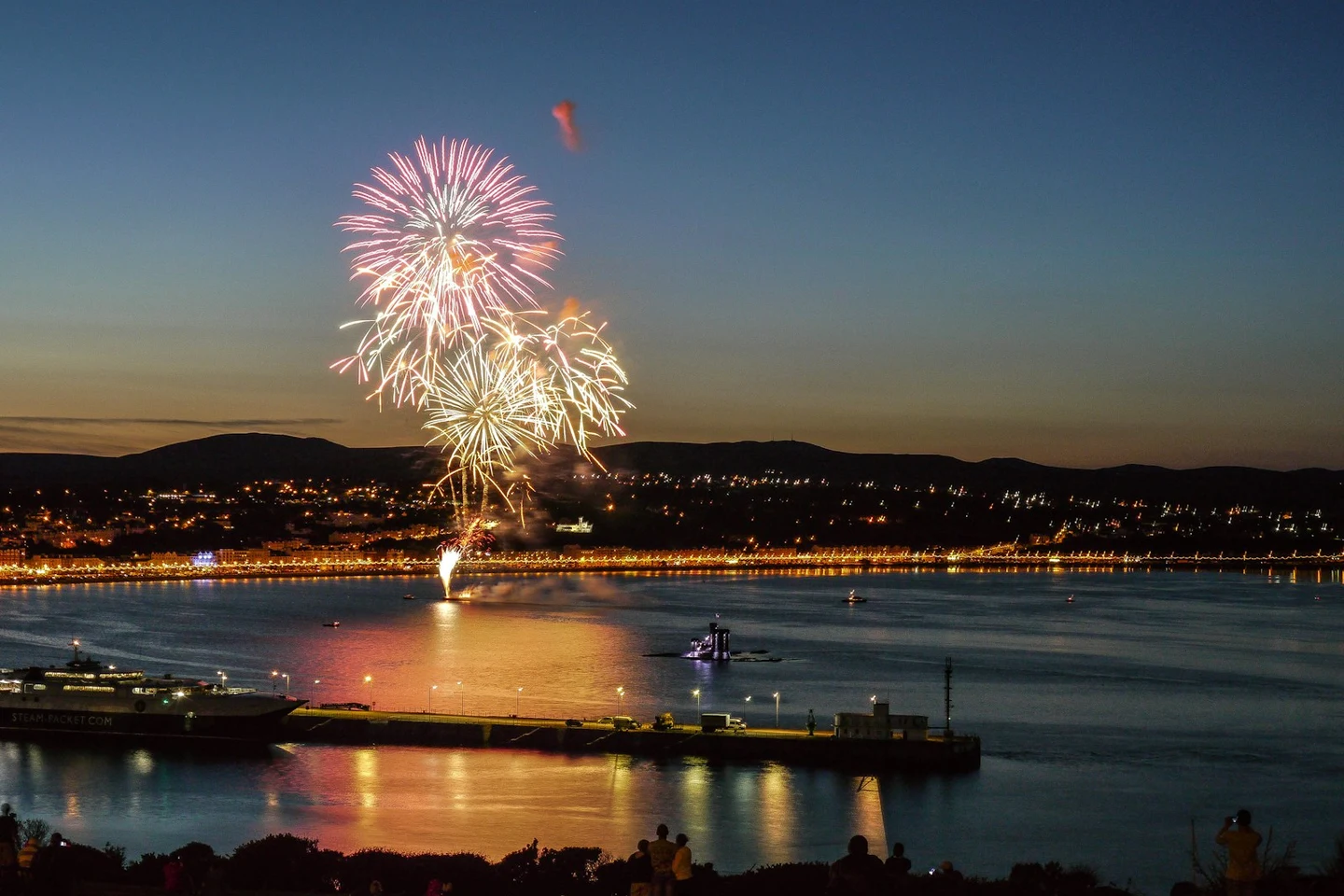 Feuerwerk über der Bucht von Douglas mit beleuchteter Promenade und Fähre