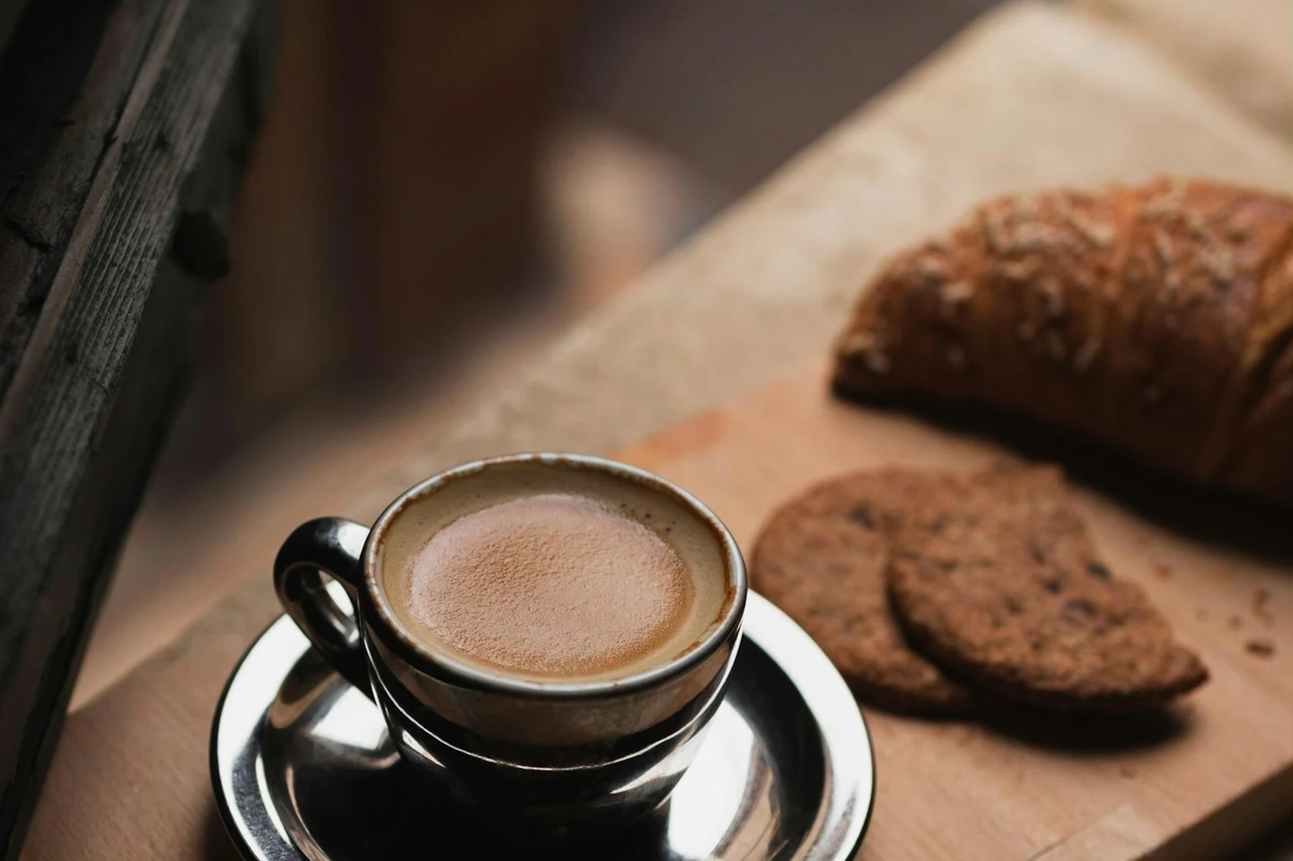 Espresso mit Croissant auf einem Holzbrett