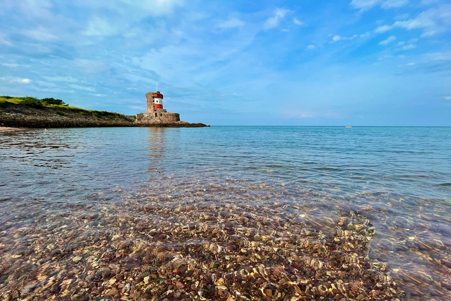 Historischer Küstenturm am klaren Wasser einer Bucht auf Jersey