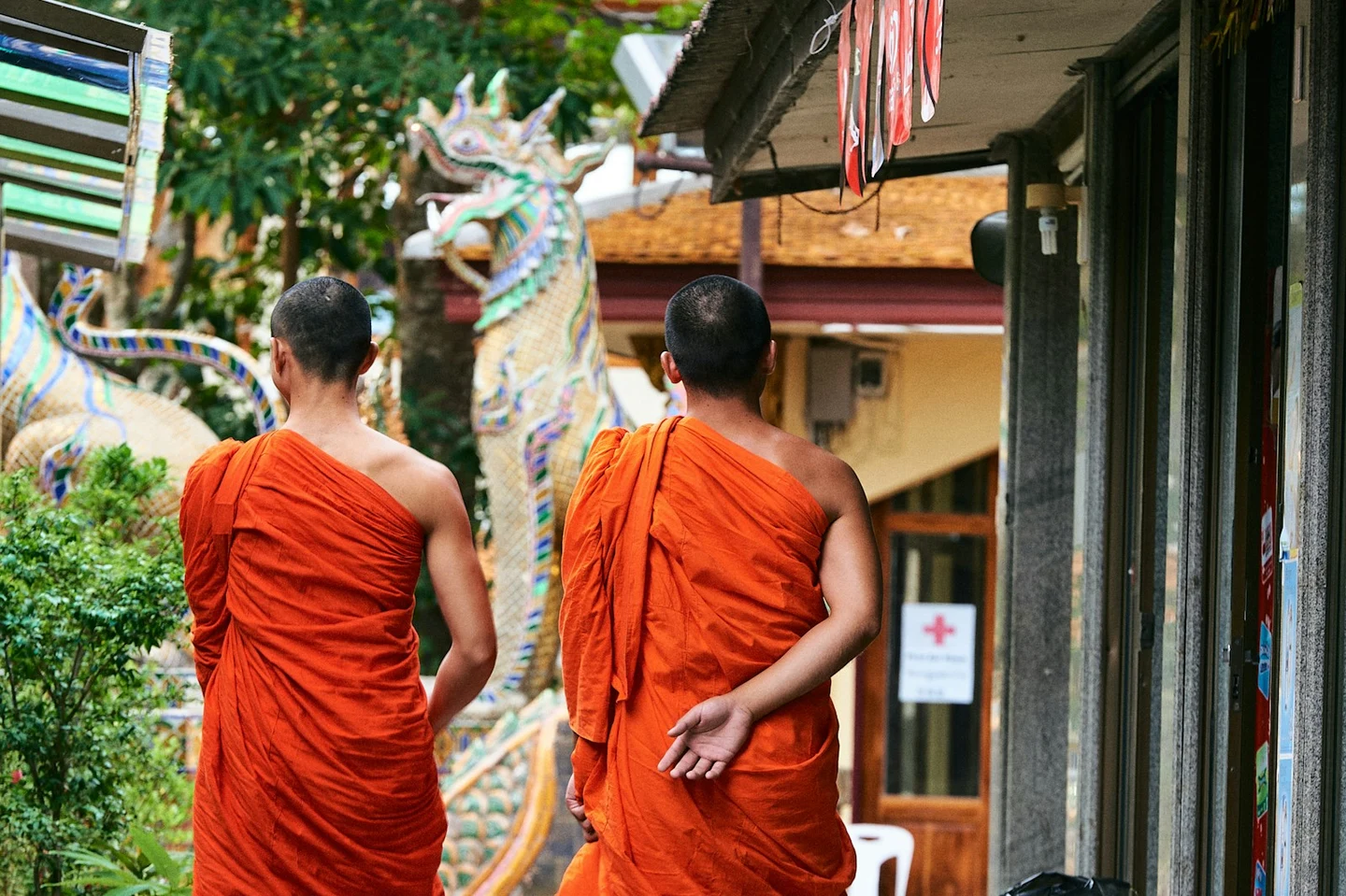 Zwei Mönche in orangefarbenen Roben auf dem Weg zum Tempel